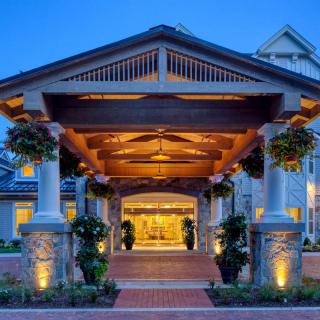A beautifully lit entrance with columns at a building during the evening.