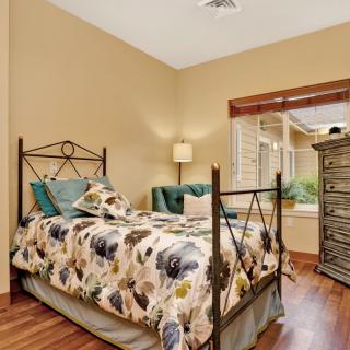 A cozy bedroom with floral bedding and wooden flooring.