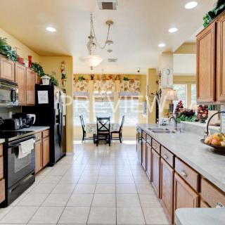 A spacious kitchen with wooden cabinets, modern appliances, and a sunlit dining area.