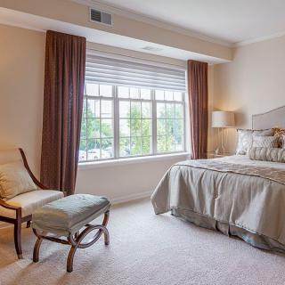 A cozy bedroom with a large window, elegant curtains, and comfortable furniture.