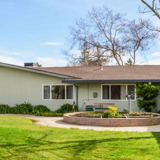 A suburban house with a well-maintained lawn and surrounding trees.
