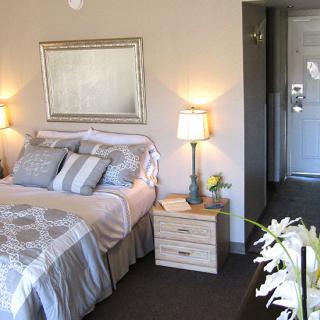 A cozy bedroom with a neatly made bed, decorative pillows, and bedside lamps.