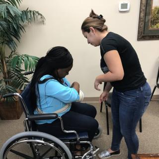 A healthcare professional assists a woman in a wheelchair.
