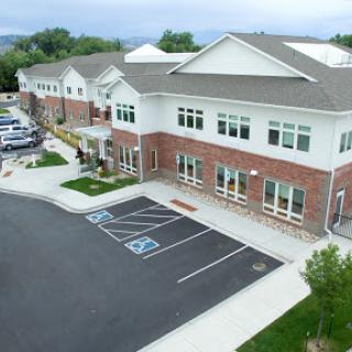 A modern residential building with accessible parking spots, surrounded by green landscaping under a cloudy sky.