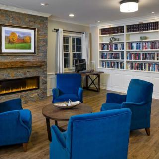 A cozy living room featuring blue chairs, a fireplace, and bookshelves.