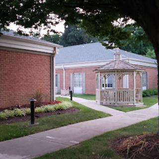 A serene view of a brick building with a charming gazebo surrounded by well-maintained landscaping.