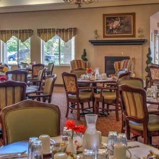 An elegant dining room set up with neatly arranged tables and chairs, featuring large windows and warm decor.