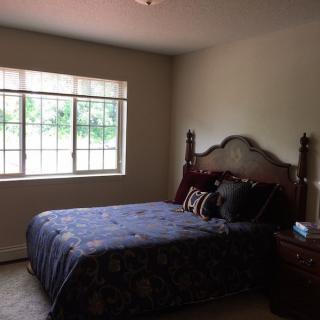 A cozy bedroom with a large window and a well-made bed.