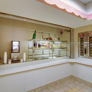 A cozy cafe interior with a display counter featuring a variety of items and bottles.