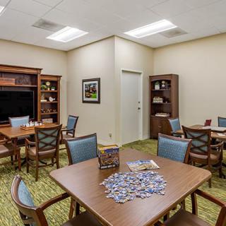 A well-lit room with multiple tables, puzzles, and bookshelves.
