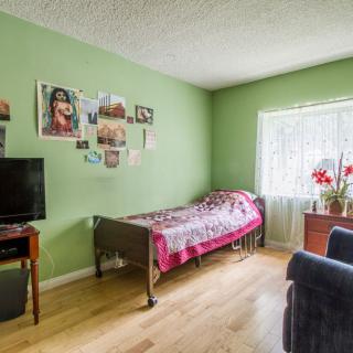 A cozy bedroom with green walls, a single bed, and a television.