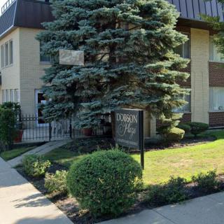 A well-maintained apartment building with landscaped greenery and a prominent sign.