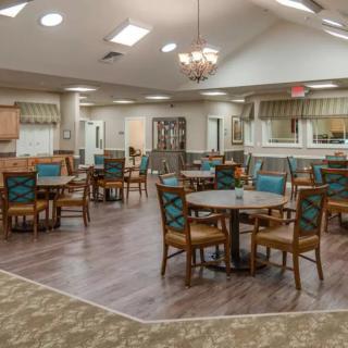 A cozy dining area with multiple tables and chairs, adorned with a chandelier and warm decor.