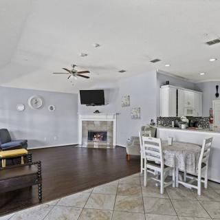 A modern open-floor plan living area featuring a living room with a fireplace, a small dining table, and a kitchen.