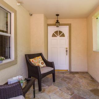 A cozy front porch with a chair, pillow, and a welcoming entry door.