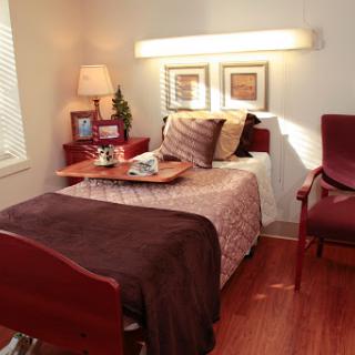 A cozy and well-decorated bedroom featuring a single bed, a bedside lamp, and two chairs.