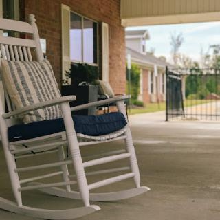 A cozy rocking chair on a porch, inviting moments of relaxation in the sunlight.