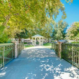 A scenic view of a house surrounded by lush greenery, with a sunlight-dappled pathway leading to its entrance.