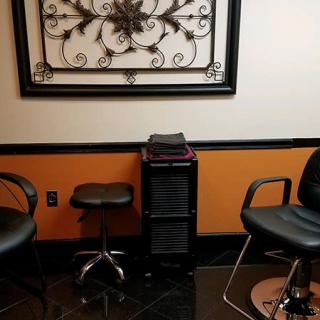 A stylish salon interior featuring chairs and a decorative wall piece.