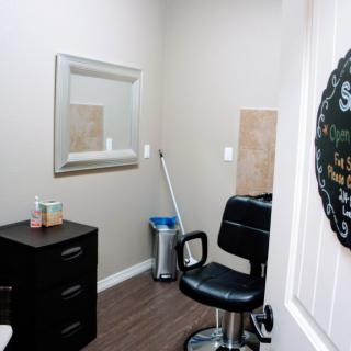 A small hair salon room featuring a chair, mirror, and storage drawers.