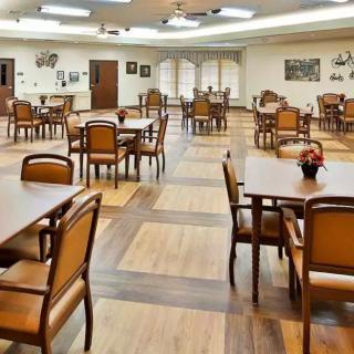 A spacious dining room with wooden floors, featuring neatly arranged tables and chairs.