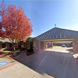 A sunny day with a building surrounded by autumn trees and a parking area.