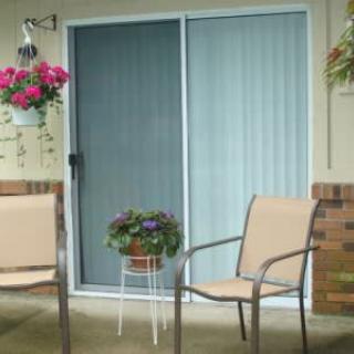 A cozy patio area with two chairs, potted plants, and a sliding glass door.