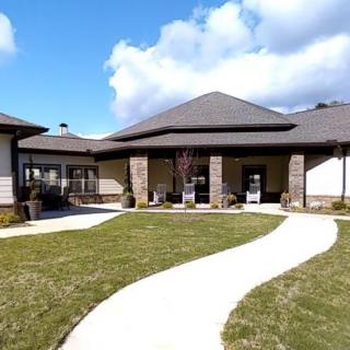A modern house with a well-maintained lawn and a winding pathway under a partly cloudy sky.