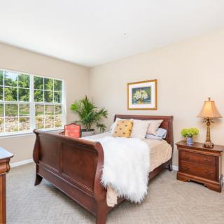 A cozy bedroom with a wooden bed, bedside tables, and large window.
