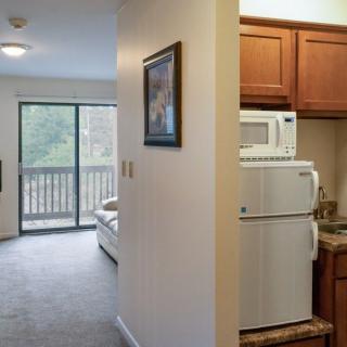 A small apartment with a kitchenette and a living area leading to a balcony.