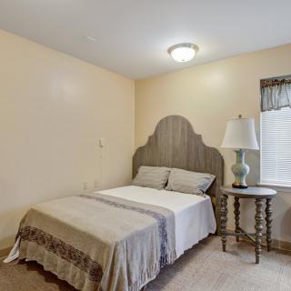 A cozy bedroom with a single bed and a side table next to a lamp.