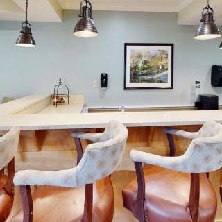 A modern bar setup featuring comfortable chairs and stylish lighting.