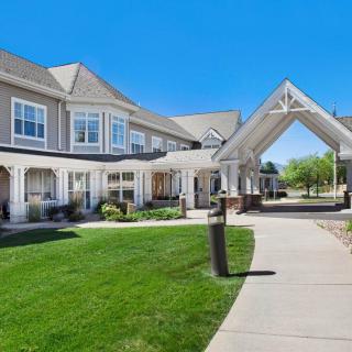 A front view of a residential building with a well-maintained lawn and clear blue skies.