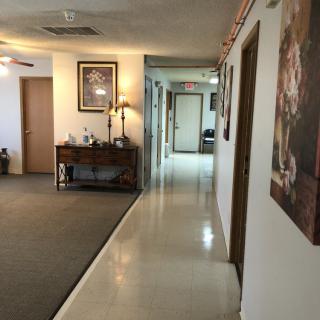 A well-lit office hallway with framed artwork and decorative furniture lining the walls.