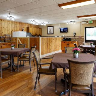 A cozy dining area featuring wooden decor, tables set for guests, and a television in the background.