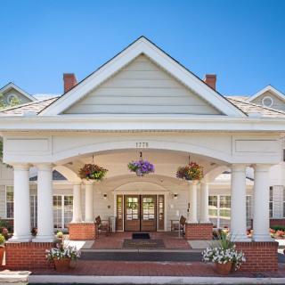 A welcoming entrance with colonial-style architecture featuring large white columns and hanging flower baskets.