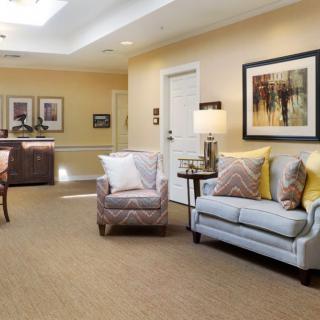 A cozy and well-decorated living room with a sofa, armchair, and wall art.