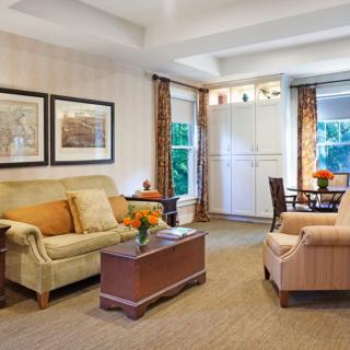 A cozy and elegantly designed living room with comfortable seating, artwork, and a small dining area.
