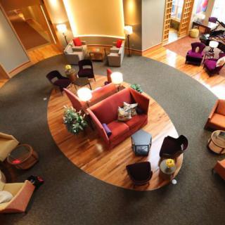 A modern hotel lobby with a cozy seating area featuring contemporary furniture and a wooden floor.