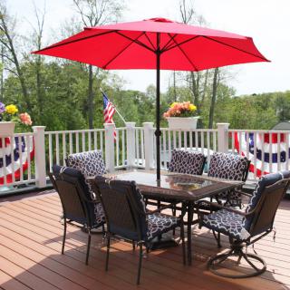 A cozy outdoor patio with a red umbrella and stylish furniture, adorned with festive decorations.