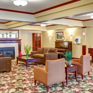 A cozy lobby area featuring sofas, armchairs, a coffee table, and a fireplace.