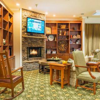 A cozy living room featuring a fireplace, bookshelves, and comfortable seating with a television mounted above the mantel.