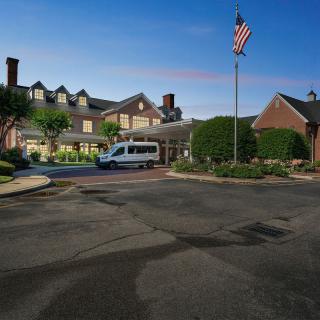 A hotel entrance in the evening with a van parked outside and an American flag on display.