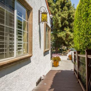 A sunny pathway beside a house with windows and a decorative lantern.
