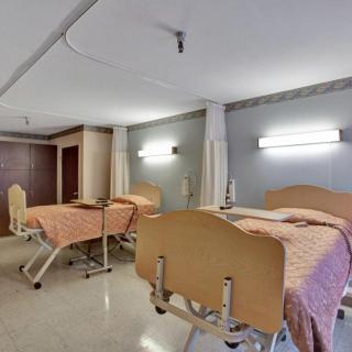 A hospital room with two adjustable beds and privacy curtains.