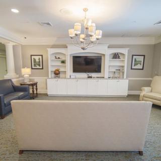 A well-lit living room with modern furniture and a central television.