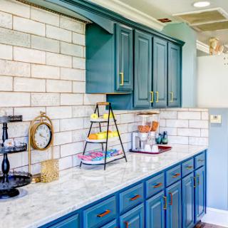 A beautifully designed kitchen featuring blue cabinetry and a stylish marble countertop with a classic subway tile backsplash.