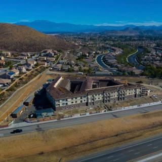 Aerial view of a building under construction in a suburban area with mountains in the background.
