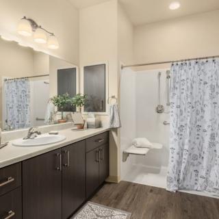 A modern bathroom featuring a large mirror, dark wood cabinetry, and a shower with a patterned curtain.