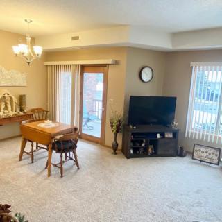 A cozy living room with a dining table, TV stand, and carpeted flooring.